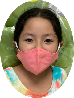 Child wearing a pink face mask, smiling